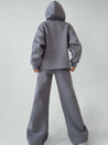 model draagt comfortabele tweedelige joggingset met trainingsbroek en hoodies met capuchon wijde broek en hoodie