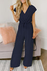 model draagt elegante jumpsuit met stretch en riem, jumpsuit met korte mouwen dames